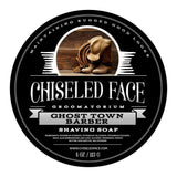 Product image of Chiseled Face Groomatorium's 'Ghost Town Barbershop' shaving soap, featuring a label with cowboy boots, a lasso rope, and leather gloves symbolizing the unique scent.